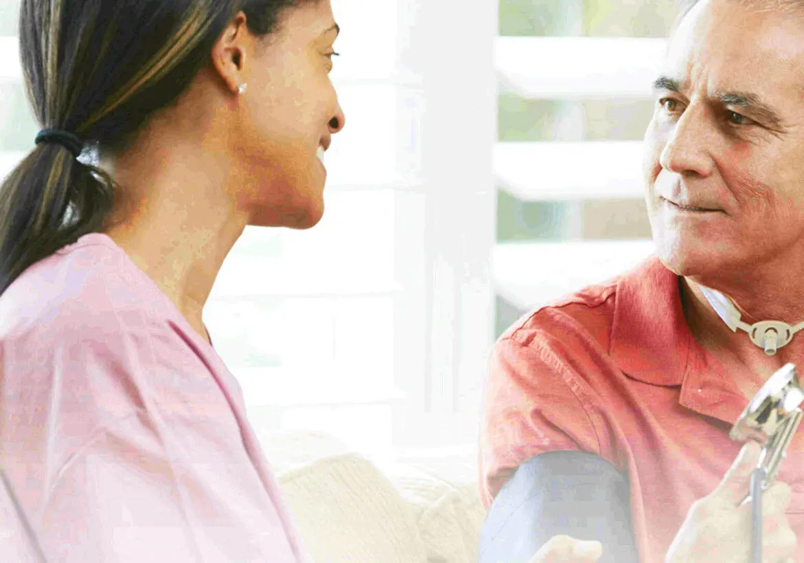 A carer and a client talking together at home